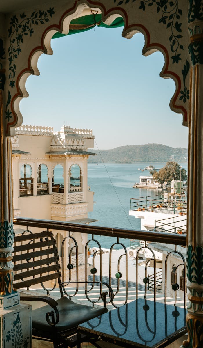 Beautiful balcony view overlooking a serene lake and traditional Indian architecture.